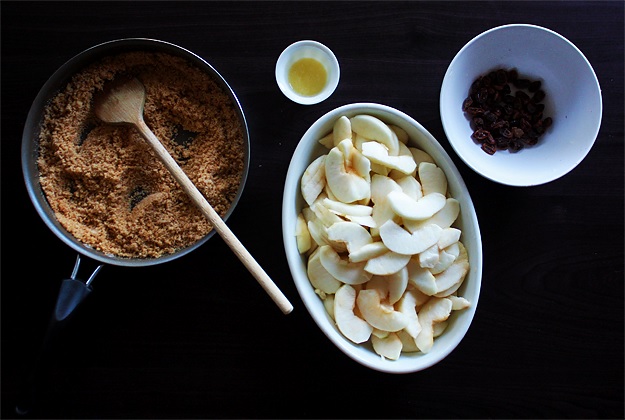 Prepare the filling: Buttered breadcrumbs mixed with sugar and cinnamon, melted butter, sliced apples, soaked raisins.