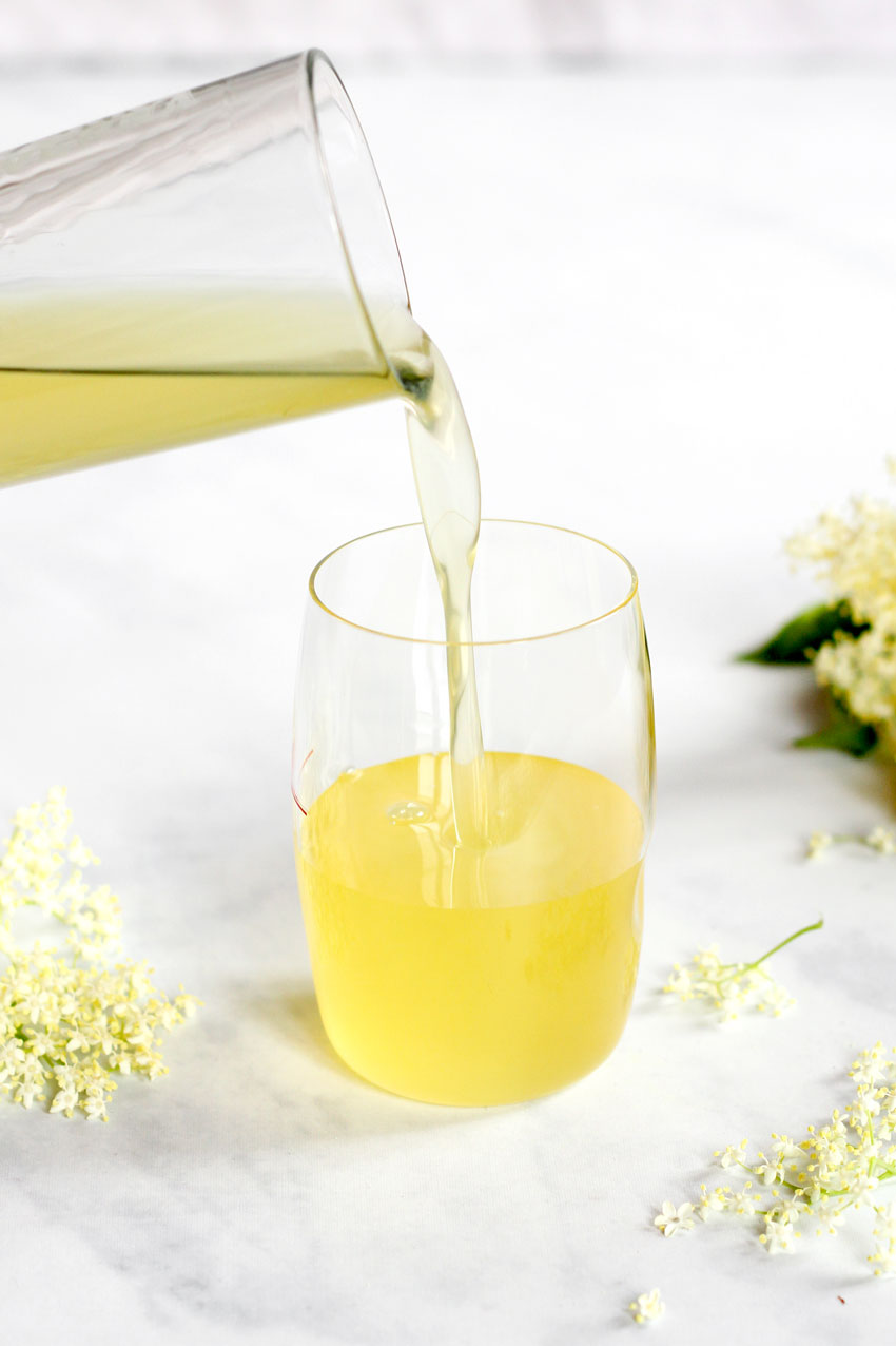 pouring elderflower syrup in glass