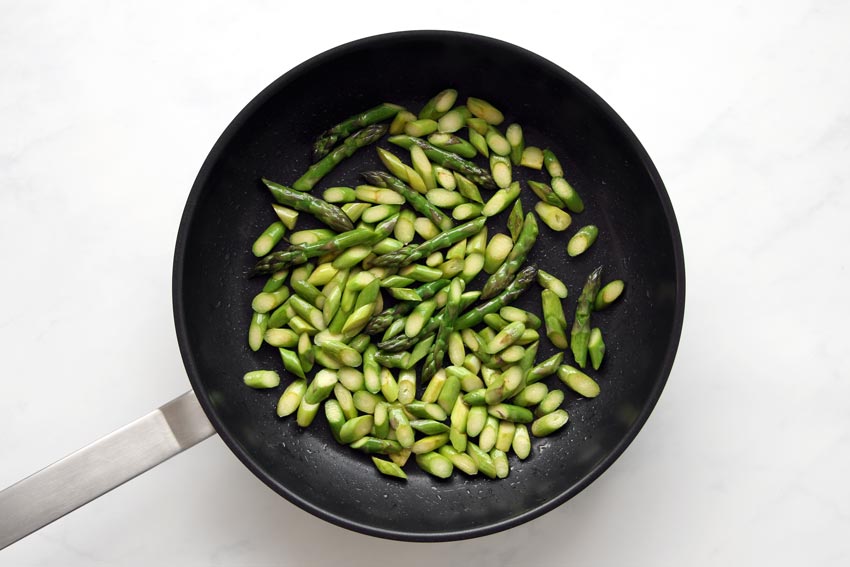 sauteeing sliced asparagus in pan