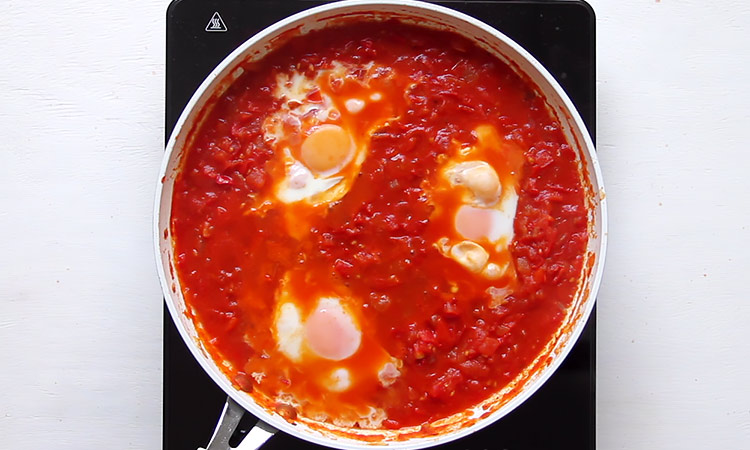 Poaching eggs in tomato sauce Shakshuka